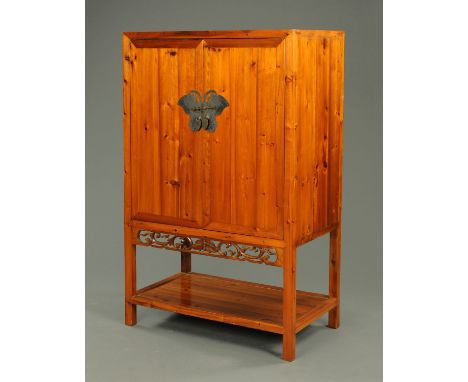 A Chinese pine cupboard, with metal lock and escutcheons, pierced apron and low shelf.  Width 105 cm. 