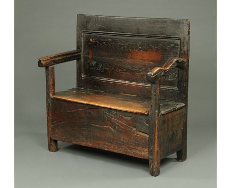 An 18th century oak box settle, with panelled back, hinged seat and raised on stile feet.  Width 107 cm.    CONDITION REPORT: