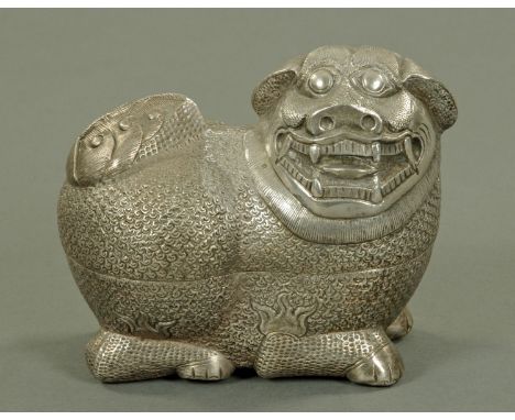 A Chinese silver coloured metal box cover in the form of a temple lion, 20th century, in recumbent pose with well coiffured h