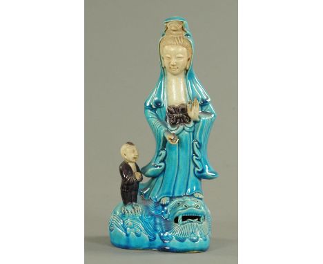 A Chinese part biscuit porcelain figure of Guan Yin, 19th century, standing in Vitarka Mudra holding a pearl, her robes in da