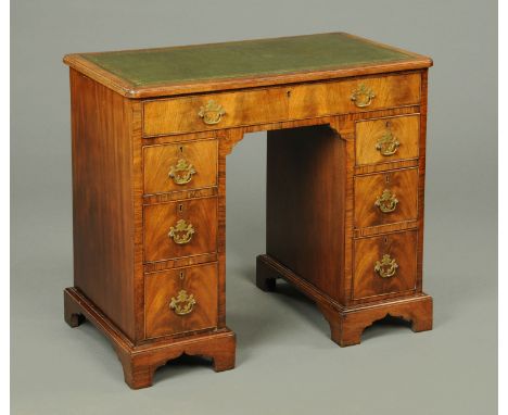 An Edwardian rosewood and walnut kneehole desk, with green tooled leather writing surface, frieze drawer and three further sh