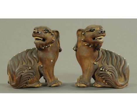 A pair of Chinese Shiwan Buddhist lions, late 19th century, each with finely detailed fur and heightened by white enamel tips