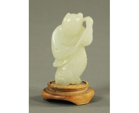 A jade figure of a young boy, early 20th century, carrying a peony flower over his shoulder, the stone generally a uniform co