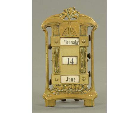 An Art nouveau brass desk calendar, late 19th century, with leaf and berry decoration and fabric scrolls for the day, date an