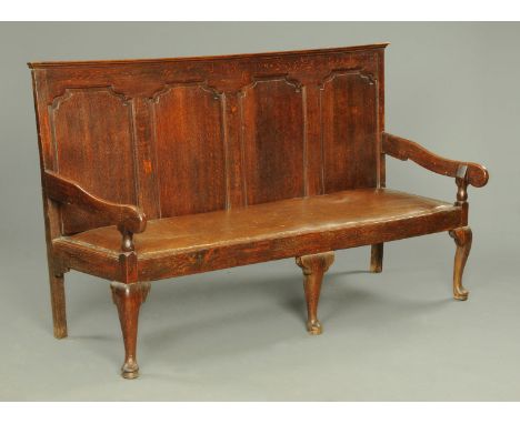 A George III oak four panelled settle, with silhouette arms, leatherette covered seat and raised on front cabriole legs.  Wid