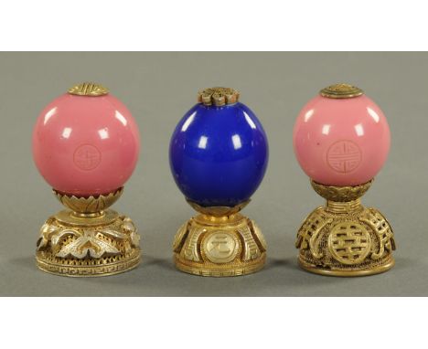 Three Chinese glass and gilt metal mounted hat finials, 20th century, comprising two opaque paint glass examples of the secon
