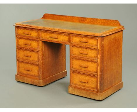 An early 20th century oak desk, with green tooled leather writing surface, series of frieze and pedestal drawers and raised o