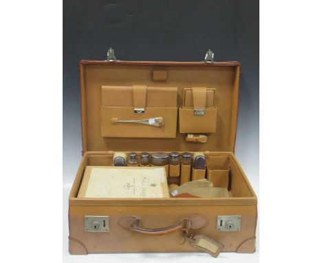 Early 20th century leather travelling case fitted for brushes, shaving mirror, blotter, shoe horn, various silver plated jars