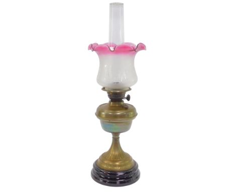 A Victorian oil lamp, with cranberry and frosted glass shade with floral etched decoration, brass central reservoir, on a flo
