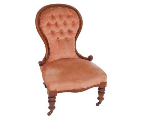 A Victorian mahogany framed nursing chair, with spoon pink upholstered button back, overstuffed seat, on cylindrical turned l