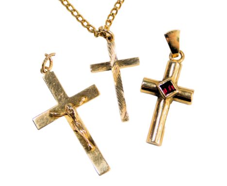 Three crucifix pendants, comprising a 9ct gold example with a raised figure, a garnet set crucifix, bearing full UK hallmarks