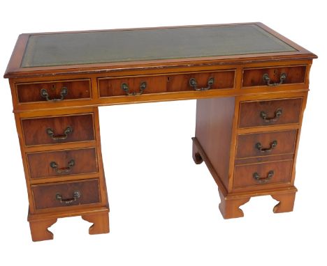 A late 20thC yew pedestal desk, the top with a moulded edge with a green tooled leather inset above an arrangement of seven d