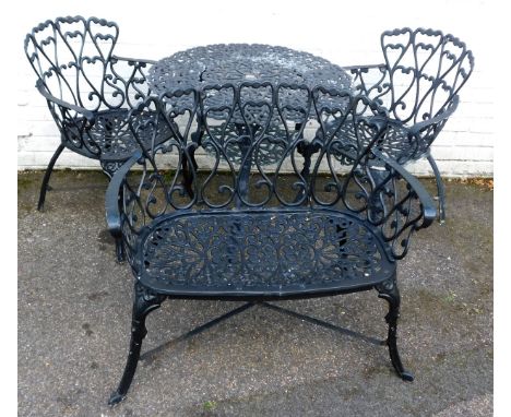 A cast metal garden set, comprising two-tier table, two chairs, and a bench, with heart motif decoration.