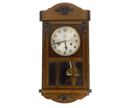A Junghans oak cased wall clock, the arched top with raised and carved scroll with silvered numeric dial, eight day movement,