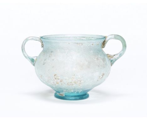  A Roman aquamarine glass two-handled drinking cup Possibly Western Empire, circa early 1st Century A.D.7cm high Footnotes:Pr