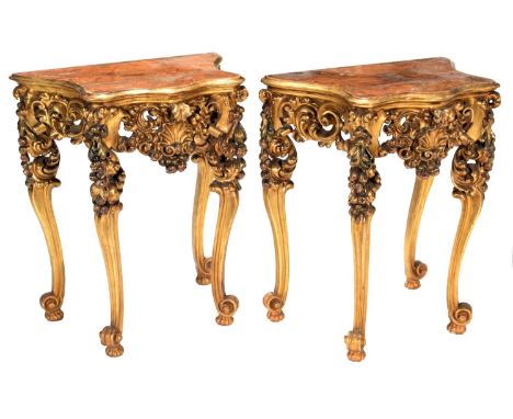 A Pair of Late 19th/Early 20th Century Continental Giltwood and Gesso Serpentine Shaped Console Tables, the moulded tops abov