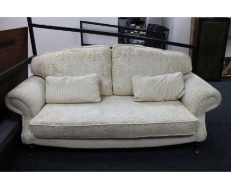 A contemporary two seater scroll arm settee in cream brocade. 