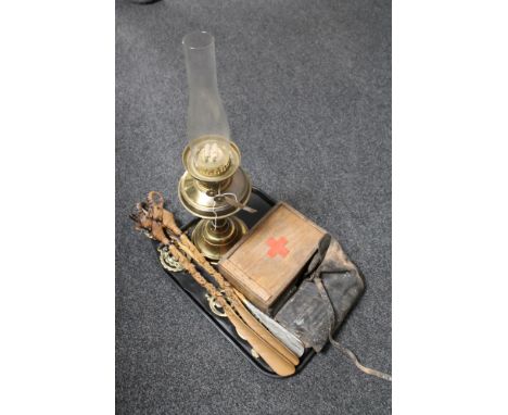 A tray of horse brasses on leather, goats head shoe horns, antique Duplex oil lamp and chimney, vintage tools in leather case