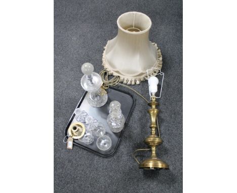 A tray of early 20th century cut glass lamp base, glass decanter, drinking glasses, brass table lamp with shade and a brass c