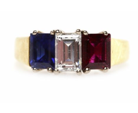 EIGHTEEN CARAT GOLD RUBY, SAPPHIRE AND DIAMOND THREE STONE RINGset with a central emerald cut diamond of approximately 0.57 c