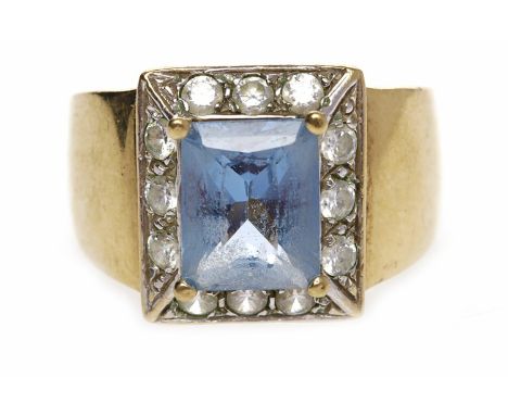 TOPAZ AND DIAMOND CLUSTER RINGset with a central rectangular step cut blue topaz 9.9mm long and surrounded by round white gem
