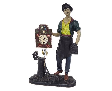 Figural painted metal mantel clock modelled as a blacksmith/clockmaker standing by his tools with a clock in either hand, 17.