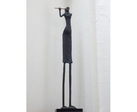 An African style cast iron figure of a woman playing the flute, raised on stepped base. H. 120cm