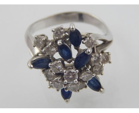 A white metal diamond and sapphire flowerhead cluster dress ring high claw set with pierced shoulder. 