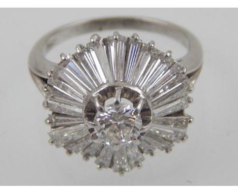 A diamond cluster ring with central brilliant cut stone surrounded by twenty four tapered baguettes claw set in a platinum ba