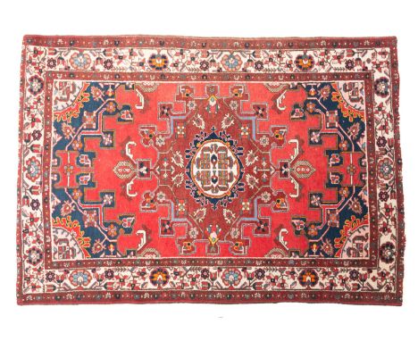A Baktiar rug, the brick red field with a central light brown shaped lozenge pole medallion, indigo and pink spandrels and ma