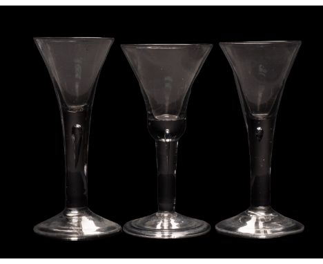 Three English wine glasses, comprising a close pair with conical shaped bowls on straight tapering stems containing a tear an