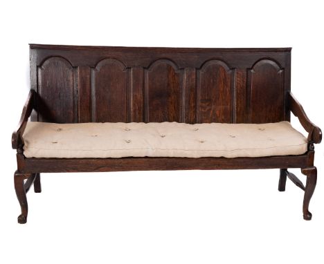 An oak panel back settle, first half 18th Century; the back rest with moulded top rail above arched panels, with down swept a
