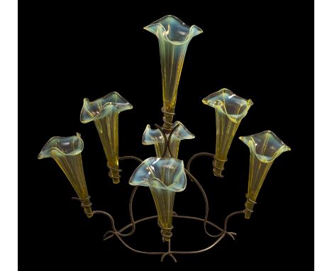 A vaseline glass epergne with seven trumpet shaped glass vases with wavy rims supported on a sinuous metal frame, 37cm high.