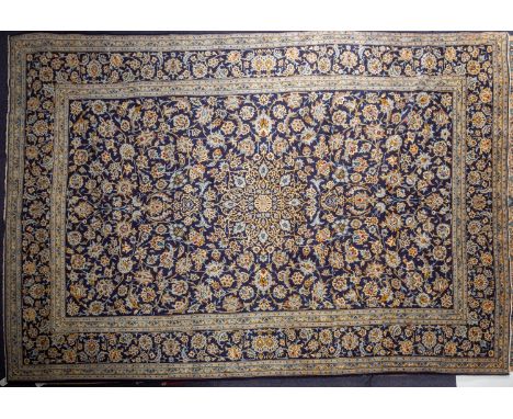 A Kashan carpet, the indigo field with a central geometric open flowerhead pole medallion, all over design of palmettes, lanc