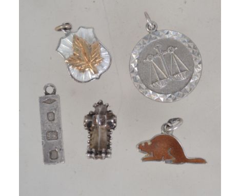A collection of 5 silver charms to include cathedral, wombat, hallmarked ingot, silver scales and Canadian maple leaf. Total 