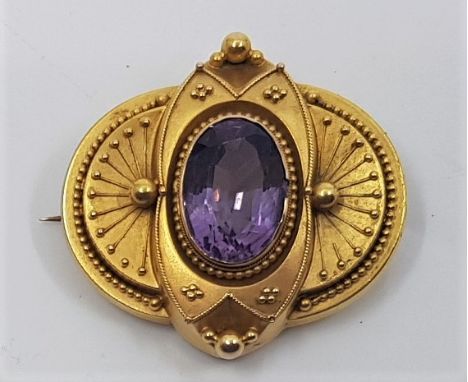 A Victorian precious yellow metal and amethyst brooch, of ovoid form with filigree and bead work decoration, set oval mixed c