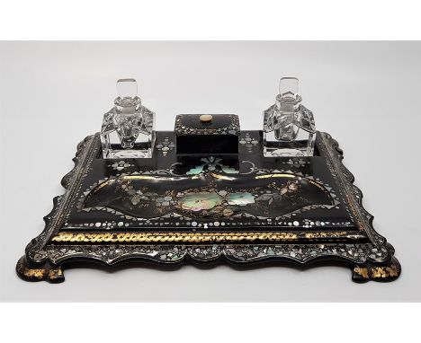 A Victorian mother of pearl inlaid papier mache desk stand, with twin glass inkwells flanking lidded nib box with shaped pen 