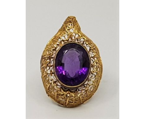 A large precious yellow metal and amethyst pendant, having&nbsp;single large oval mixed cut amethyst set within heavy wire wo