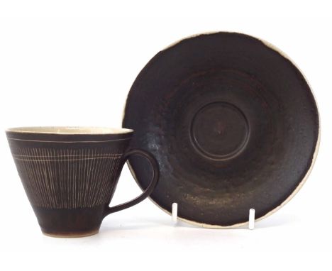 Lucie Rie cup and saucer, the brown glazed body has scratched liner decoration, impressed monograms, (2) 7cm high     Artists