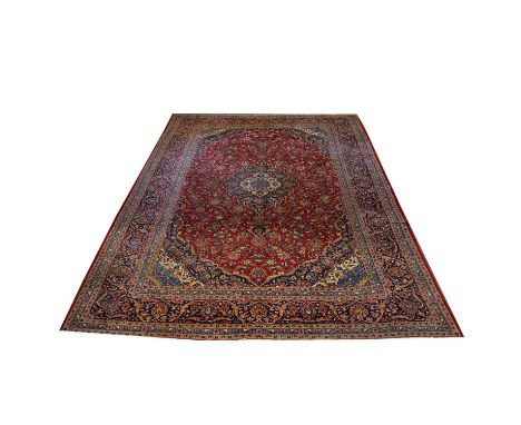 Large Tabriz carpet, with large central medallion in cream and navy against a crimson field with allover flower design, enclo