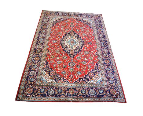 Large Tabriz carpet, with large central medallion in cream and navy against a crimson field with allover flower design, enclo