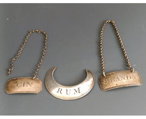 A silver decanter label, Gin, another, Brandy, and a plated decanter label, Rum (3) 