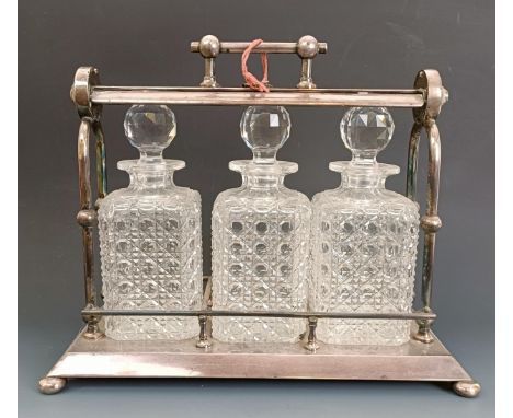A silver plated three bottle tantalus, with a Dr Christopher Dresser style handle, on bun feet, 39 cm wideWith two keys 