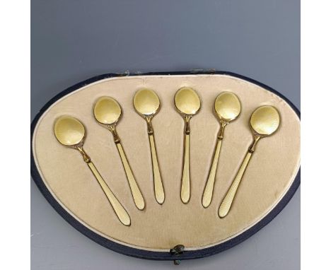 A set of six silver gilt and yellow enamel teaspoons, boxedBox hinges are broken, the lid is detached 