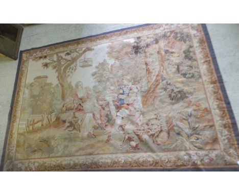 An Aubusson tapestry carpet / wall hanging depicting a pastoral scene with figures in 18th Century dress, a dog and lambs at 