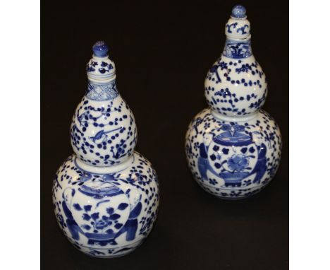 A pair of Chinese porcelain gourd shaped vases and covers, each painted in underglaze blue with figures beside a spherical va