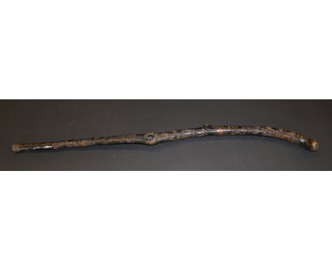 A 19th Century Northern European carved and stained wooden stick with all-over face mask, skull, hands, love heart and scroll