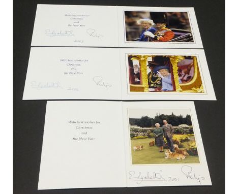 A Christmas card from Her Majesty The Queen and Prince Philip depicting The Queen and Prince Philip in gardens with five dogs