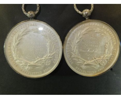 Two white metal Birmingham Agricultural Exhibition Society medallions depicting cattle and sheep and a pig to one side, the o