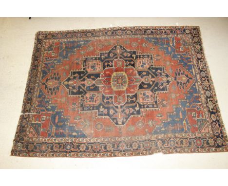 A Caucasian carpet, the central medallion in blue, salmon, red, green and cream on a red medallion decorated border, with blu